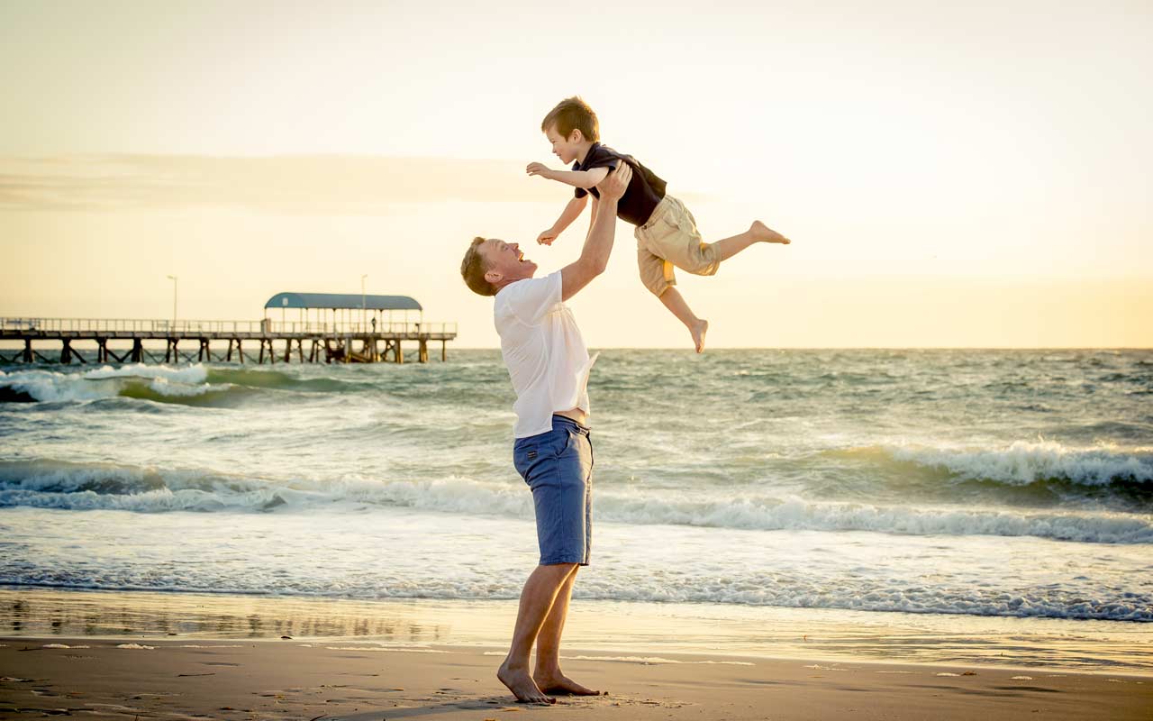 Песня держись отец. Парень с ребенком со спины. Папа держит сына на руках. Отец держит ребенка. Счастливые папа и сын в море.